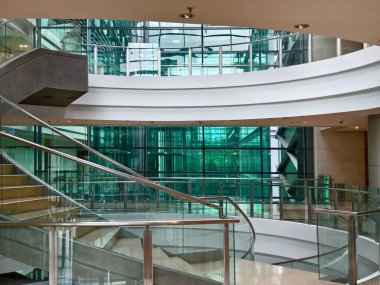 Modern bir binada cam parmaklıklı güzel tasarlanmış spiral bir merdiven..