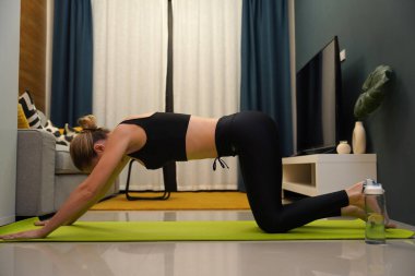 Genç bir kadının modern bir ev ortamında keyifli bir yoga uygulaması var. 