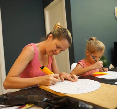 Bir anne ve küçük kızı, yaratıcılığı teşvik eden renkli bir resim faaliyetinde bulunuyorlar.