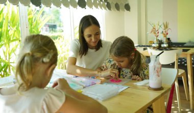 Sanat öğretmeni atölyede iki kıza termo mozaik montajı öğretiyor. 