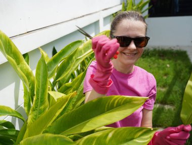 Genç bir kadın güzel bahçesini süslüyor canlı yeşilliğini ve açık hava aktivitelerine olan aşkını sergiliyor.