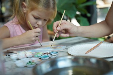 Genç bir anne ve kızı evde sanatsal bir seansın keyfini çıkarıyorlar. Renkli sanatlarıyla meşgul ve bağ kuruyorlar.