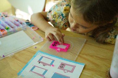 Sanat öğretmeni atölyede iki kıza termo mozaik montajı öğretiyor. 