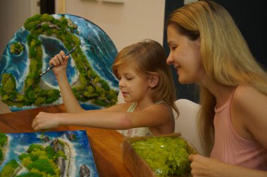 Genç bir anne ve kızı birlikte canlı doğal manzaralar yaratıyor. 