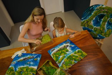 Genç bir anne ve kızı birlikte canlı doğal manzaralar yaratıyor. 