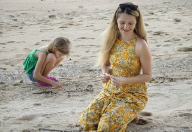 Kumsalda deniz kabuğu toplarken bir anne ve kızı