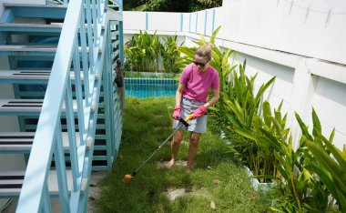 Genç bir kadın güzel bahçesini süslüyor canlı yeşilliğini ve açık hava aktivitelerine olan aşkını sergiliyor.