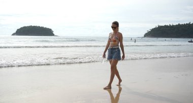 Genç bir kadın kumsalda güzel bir günün tadını çıkarıyor. 