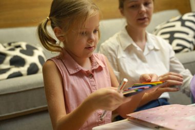 Genç bir anne ev ödevleriyle kızına destek olur.