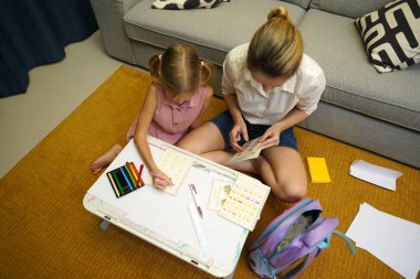 Genç bir anne ev ödevleriyle kızına destek olur.