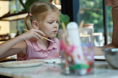 Genç bir anne ve kızı evde sanatsal bir seansın keyfini çıkarıyorlar. Renkli sanatlarıyla meşgul ve bağ kuruyorlar.