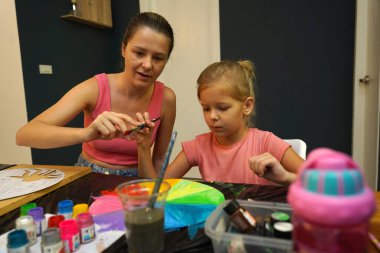 Bir anne ve küçük kızı, yaratıcılığı teşvik eden renkli bir resim faaliyetinde bulunuyorlar.