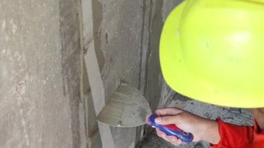 Yetenekli bir işçi titizlikle duvara çimento karışımı sürüyor. Mükemmel bir son için mala kullanıyor.