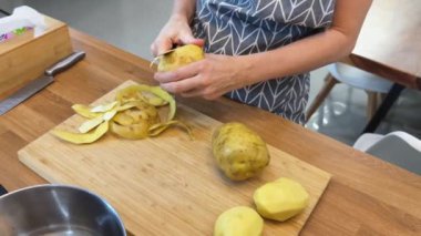 Bir kadın güzel tasarlanmış modern mutfakta ustalıkla lezzetli bir patates hazırlıyor.