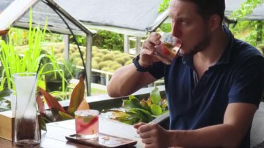 Bir adam modern bir kafe ortamında keyifli bir yemek ve içecekten zevk alıyor.