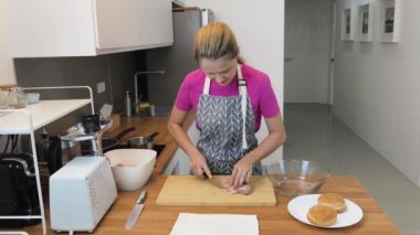 Genç bir kadın, modern mutfakta çiğ eti hamburgerlere hazırlıyor. 