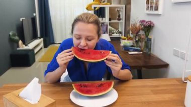 Genç bir kadın, sıcacık mutfağında nefis bir şekilde taze karpuz keser ve zevk alır.