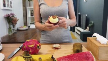 Güzel tasarlanmış modern mutfakta taze meyve kesen genç bir kadın.