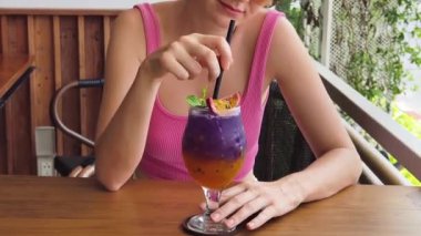  Bir kadın açık havada huzurlu bir kafede renkli bir içkiden hoşlanır.