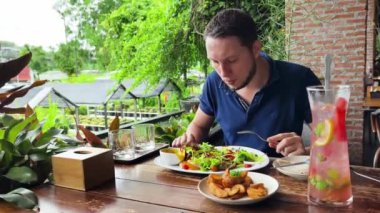 Bir adam modern bir kafe ortamında keyifli bir yemek ve içecekten zevk alıyor.