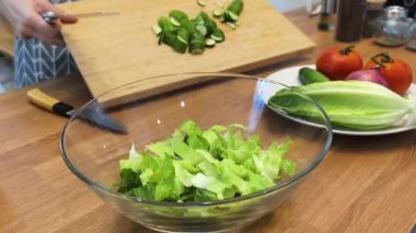 Taze sebzelerden ve çeşitli malzemelerden oluşan lezzetli bir salata pişiren bir şef. 