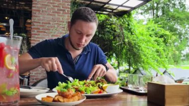 Bir adam modern bir kafe ortamında keyifli bir yemek ve içecekten zevk alıyor.