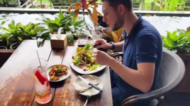 Bir adam modern bir kafe ortamında keyifli bir yemek ve içecekten zevk alıyor.