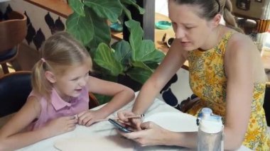 Genç bir anne ve kızı evde sanatsal bir seansın keyfini çıkarıyorlar. Renkli sanatlarıyla meşgul ve bağ kuruyorlar.