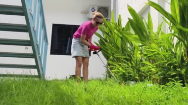 Genç bir kadın güzel bahçesini süslüyor canlı yeşilliğini ve açık hava aktivitelerine olan aşkını sergiliyor.