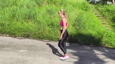 Bir kadın, yemyeşil ve çarpıcı kıyı manzaralarıyla çevrili güzel, dolambaçlı bir yolda koşuyor.