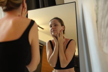 Genç bir kadın güzel pastel temalı yatak odasında huzurlu bir sabahın tadını çıkarıyor.