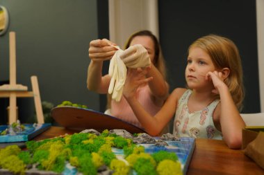 Genç bir anne ve kızı birlikte canlı doğal manzaralar yaratıyor. 