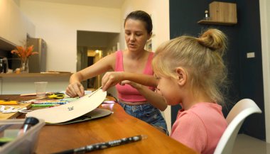 Bir anne ve küçük kızı, yaratıcılığı teşvik eden renkli bir resim faaliyetinde bulunuyorlar.