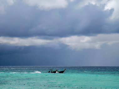 Huzurlu ve sakin bir ada manzarası kristal berrak sular ve üzerinde büyüleyici bulutlar barındırıyor.