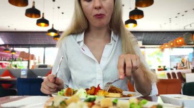 Bir kadın, modern bir kafe ortamında hoş bir yemeğin tadını çıkarıyor.