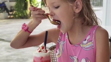Küçük bir kız mutlu bir şekilde dondurmanın tadını çıkarıyor.