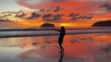 Gün batımında sakin sahil sahnesinde koşan ve yürüyen bir kadın. 