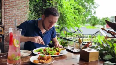 Bir adam modern bir kafe ortamında keyifli bir yemek ve içecekten zevk alıyor.