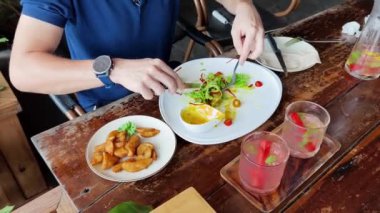 Bir adam modern bir kafe ortamında keyifli bir yemek ve içecekten zevk alıyor.