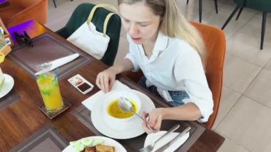 Bir kadın, modern bir kafe ortamında hoş bir yemeğin tadını çıkarıyor.