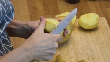 Bir kadın güzel tasarlanmış modern mutfakta ustalıkla lezzetli bir patates hazırlıyor.