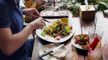 Bir adam modern bir kafe ortamında keyifli bir yemek ve içecekten zevk alıyor.