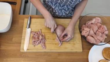 Genç bir kadın, modern mutfakta çiğ eti hamburgerlere hazırlıyor. 