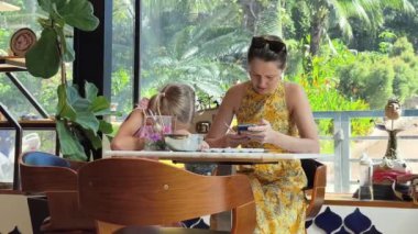 Genç bir anne ve kızı evde sanatsal bir seansın keyfini çıkarıyorlar. Renkli sanatlarıyla meşgul ve bağ kuruyorlar.