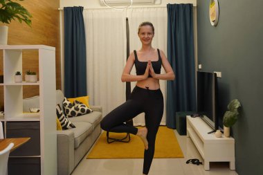 Genç bir kadının modern bir ev ortamında keyifli bir yoga uygulaması var. 