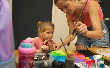 Bir anne ve küçük kızı, yaratıcılığı teşvik eden renkli bir resim faaliyetinde bulunuyorlar.