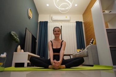 Genç bir kadının modern bir ev ortamında keyifli bir yoga uygulaması var. 