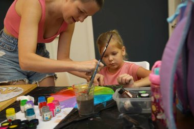 Bir anne ve küçük kızı, yaratıcılığı teşvik eden renkli bir resim faaliyetinde bulunuyorlar.