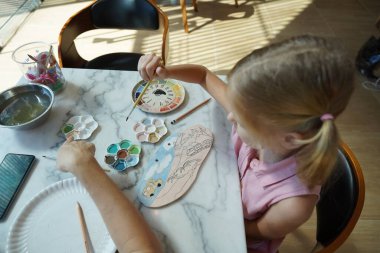 Genç bir anne ve kızı evde sanatsal bir seansın keyfini çıkarıyorlar. Renkli sanatlarıyla meşgul ve bağ kuruyorlar.