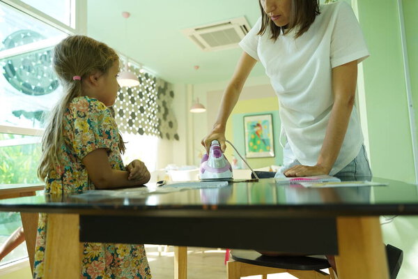 Art teacher teaches in workshop two girls how to assemble a thermo mosaic 